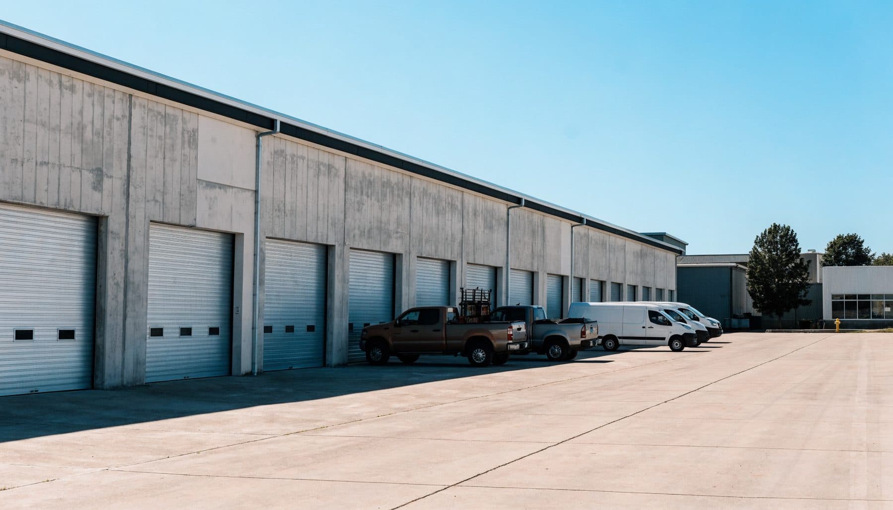 A row of ground-level roll-up doors at a small bay industrial park
